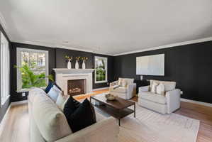 Living area featuring a high end fireplace, light wood-type flooring, and ornamental molding