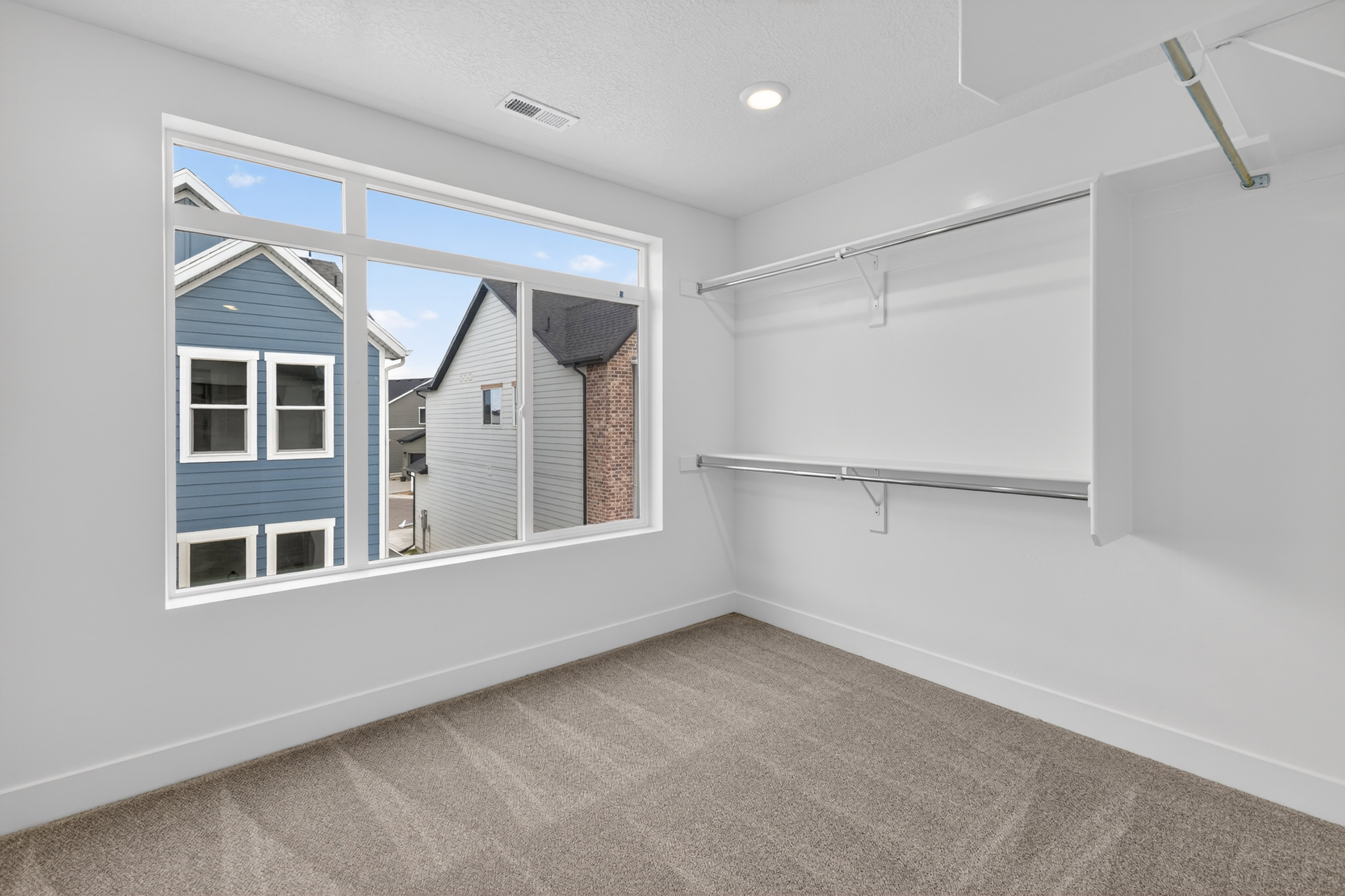Walk in closet with light colored carpet