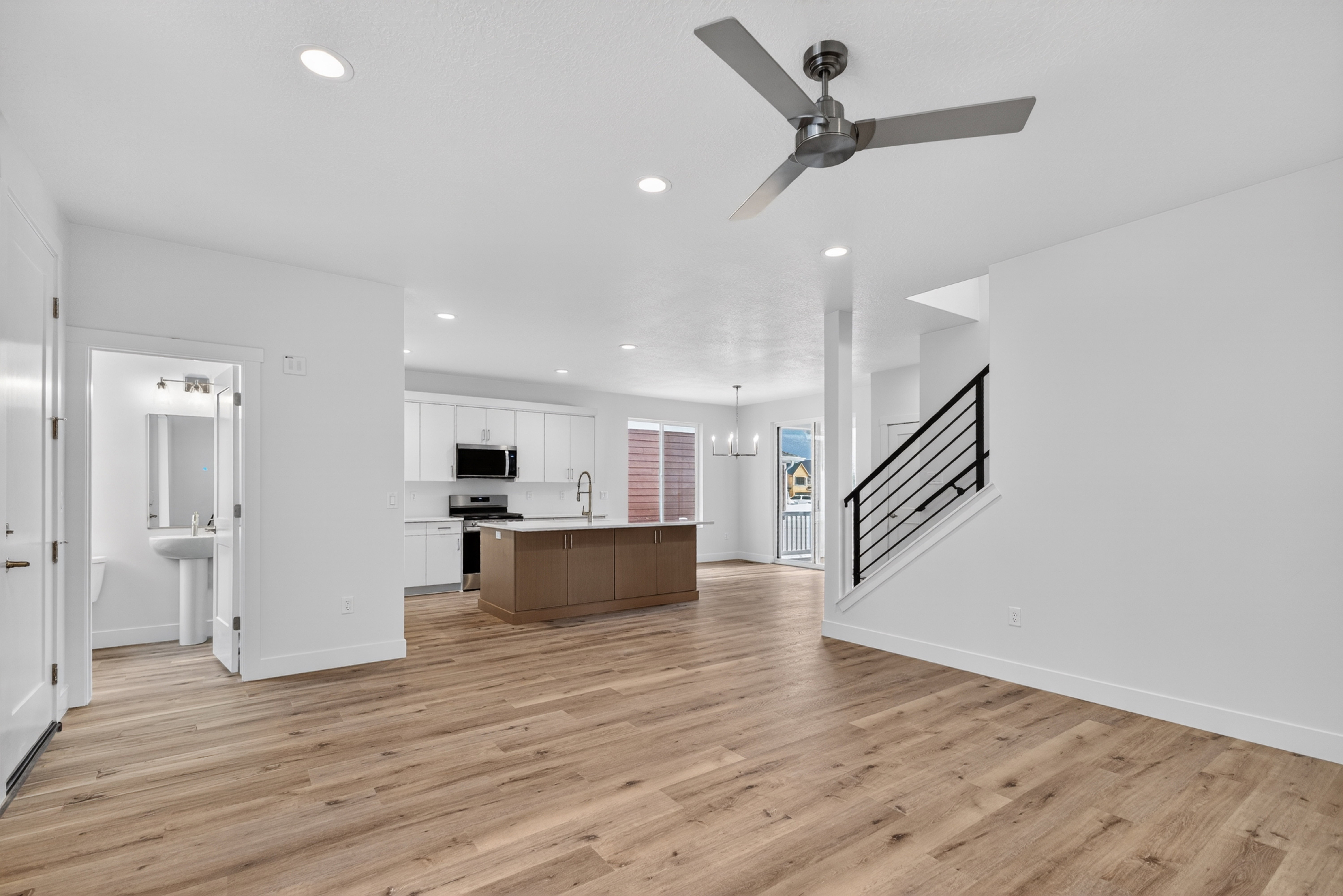 Kitchen featuring open floor plan, a kitchen island with sink, light countertops, light wood-style flooring, and ceiling fan