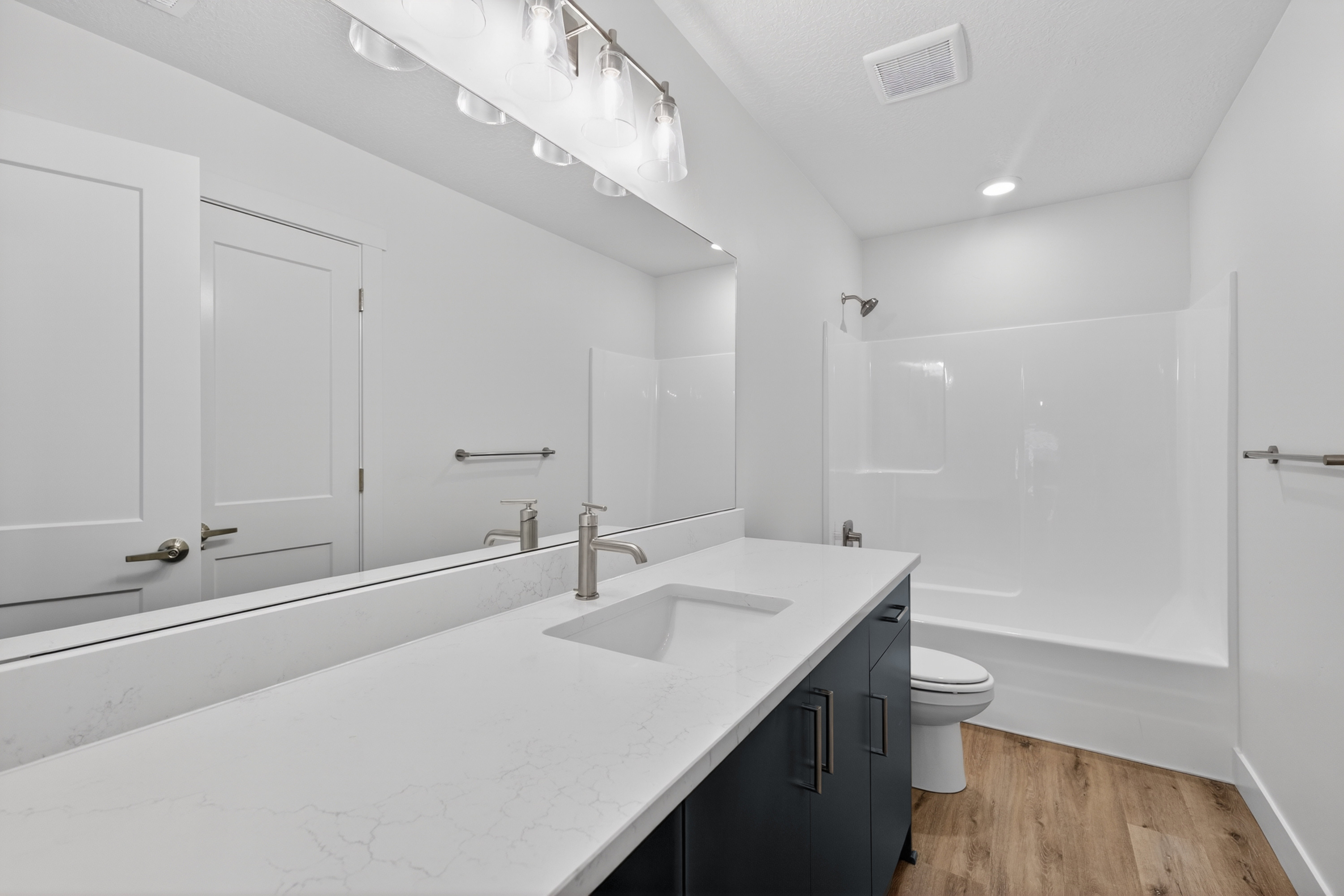 Bathroom with vanity, light wood-type flooring, and shower / tub combination