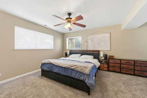 Carpeted bedroom featuring a ceiling fan and baseboards