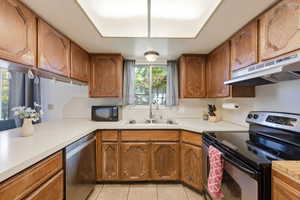 Kitchen featuring stainless steel appliances, wood finish cabinetry, light countertops, and light tile patterned floors