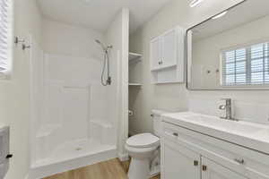 Full bath with healthy amount of natural light, vanity, a stall shower, and light wood finished floors