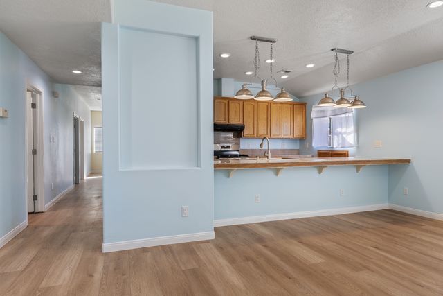 Kitchen featuring a kitchen bar, wood finish cabinetry, light wood finished floors, stainless steel range oven, and a peninsula