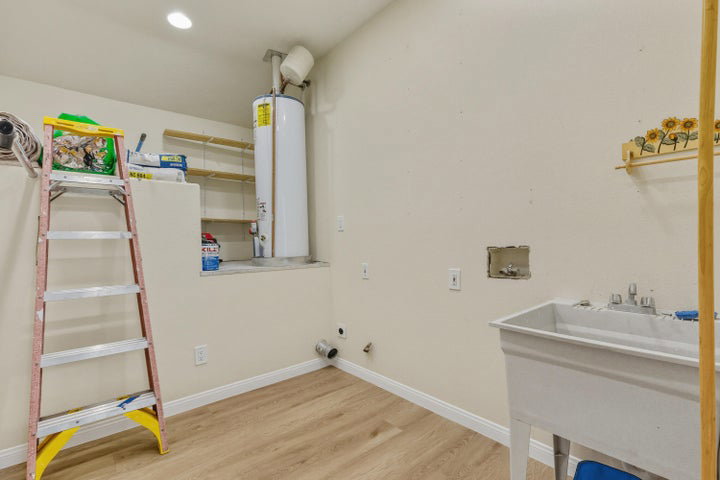Laundry area with hookup for a washing machine, gas dryer hookup, gas water heater, light wood finished floors, and recessed lighting