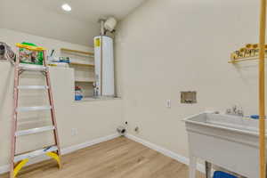 Laundry area with hookup for a washing machine, gas dryer hookup, gas water heater, light wood finished floors, and recessed lighting