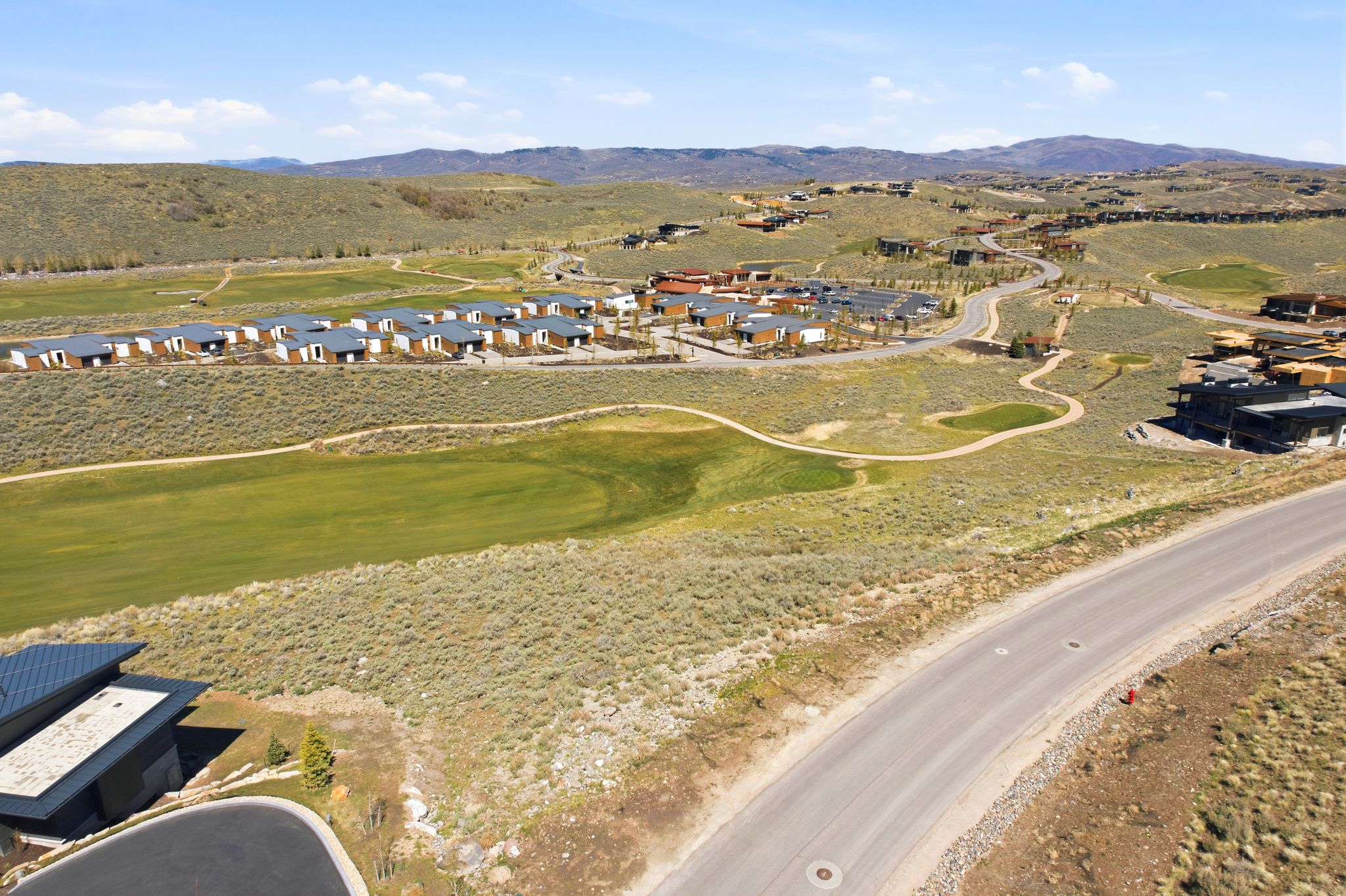 Aerial view of property's location with a mountain backdrop, nearby suburban area, and a golf course