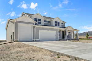 Craftsman-style house featuring concrete driveway, a mountain view, covered porch, and an attached garage