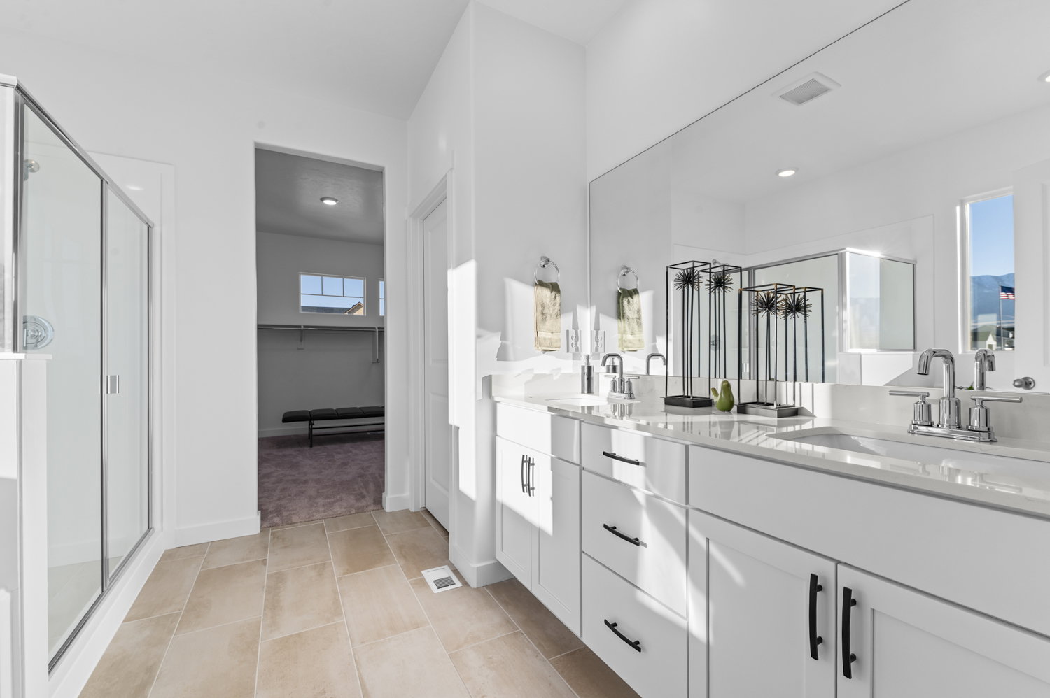 Bathroom featuring double vanity, a walk in closet, a stall shower, and light tile patterned floors
