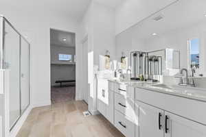 Bathroom featuring double vanity, a walk in closet, a stall shower, and light tile patterned floors