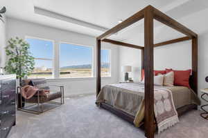 Bedroom featuring a mountain view, light carpet, and multiple windows