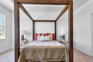 Bedroom featuring light carpet and baseboards