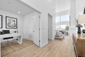 Office featuring light wood-style floors, a high ceiling, and recessed lighting