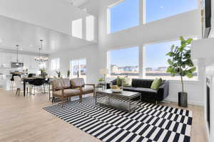 Living area featuring a fireplace, light wood-style flooring, a chandelier, and a high ceiling