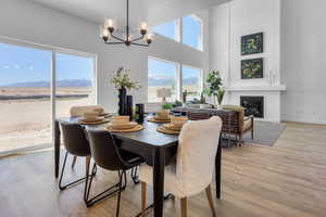 Dining space featuring a mountain view, hanging lights, a high ceiling, light wood-type flooring, and a glass covered fireplace