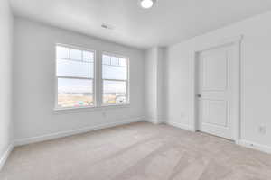 Spare room with baseboards and light colored carpet