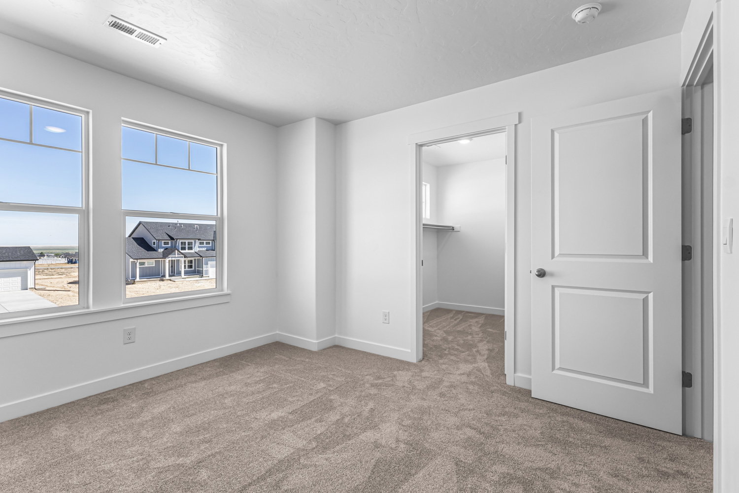 Unfurnished bedroom with a walk in closet and light colored carpet