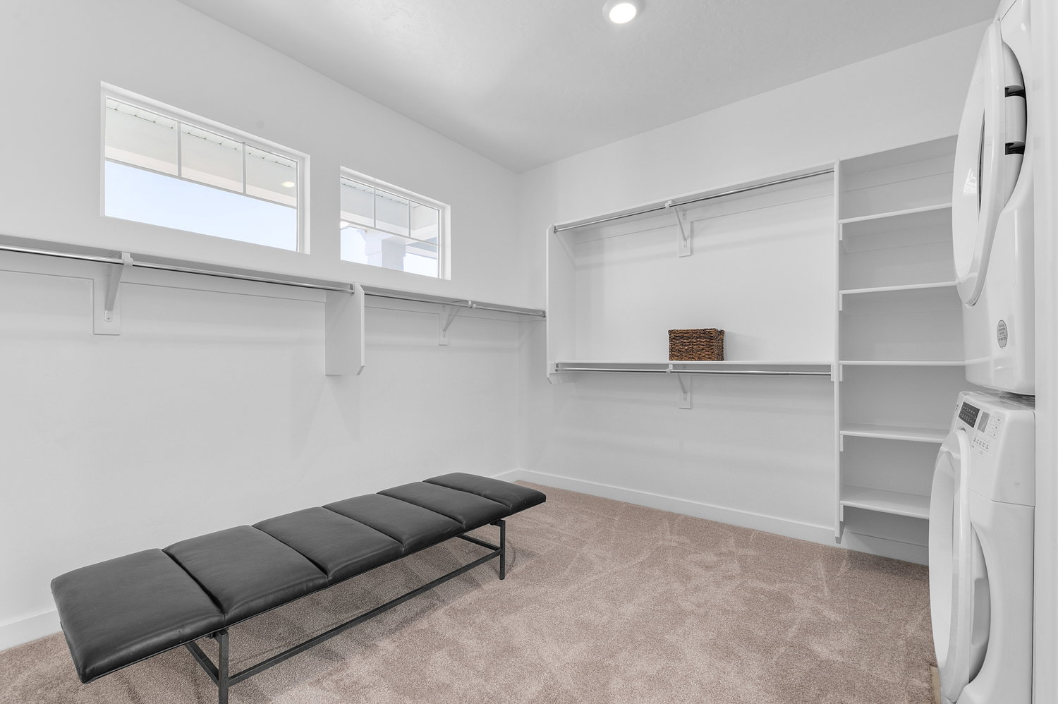 Walk in closet with light carpet and stacked washer / dryer