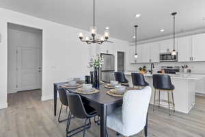 Dining room with hanging lights and light wood finished floors