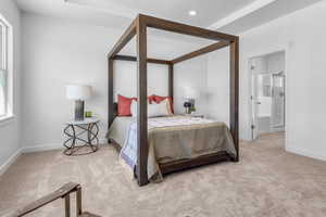 Bedroom with light carpet, ensuite bath, and multiple windows