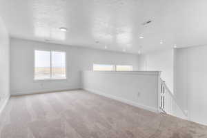 Empty room with carpet flooring and a textured ceiling
