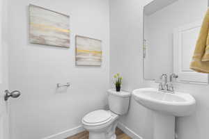 Half bath with toilet and wood finished floors