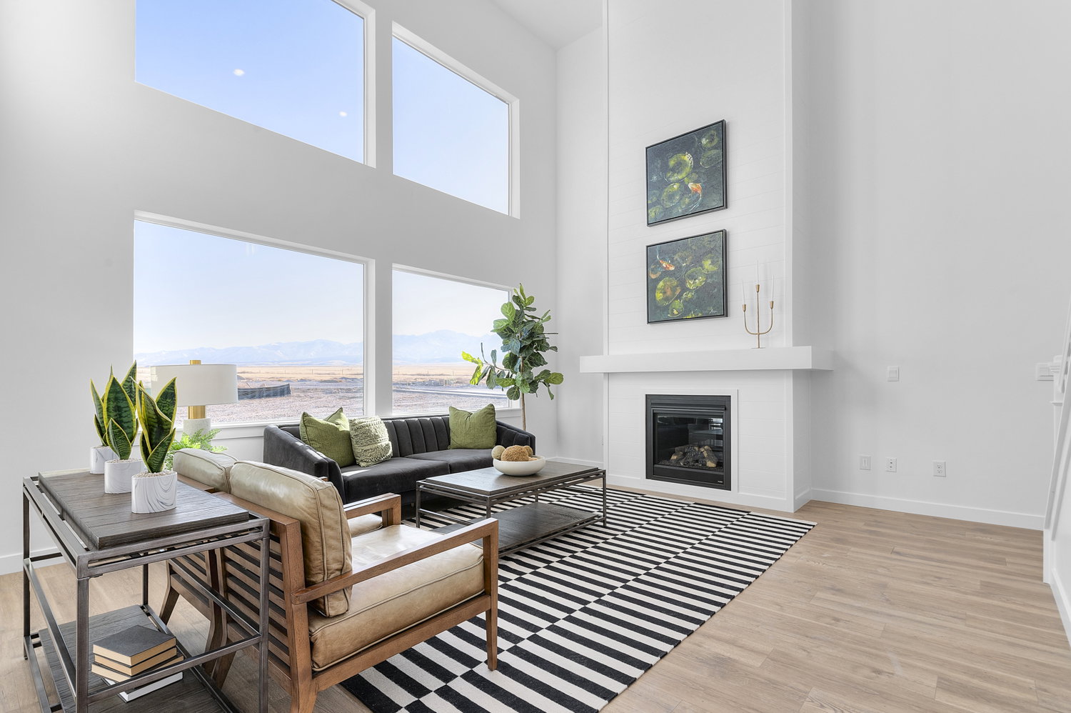 Living area featuring a high ceiling, light wood-style floors, a glass covered fireplace, and a mountain view