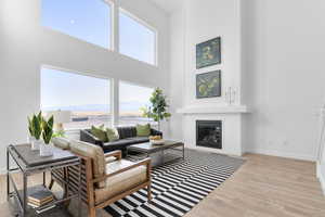 Living area featuring a high ceiling, light wood-style floors, a glass covered fireplace, and a mountain view