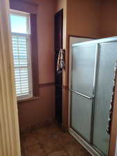 Full bathroom with wainscoting, a stall shower, and wood walls