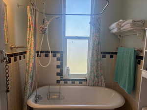 Full bathroom with shower / bath combo with shower curtain, a wainscoted wall, and tile walls