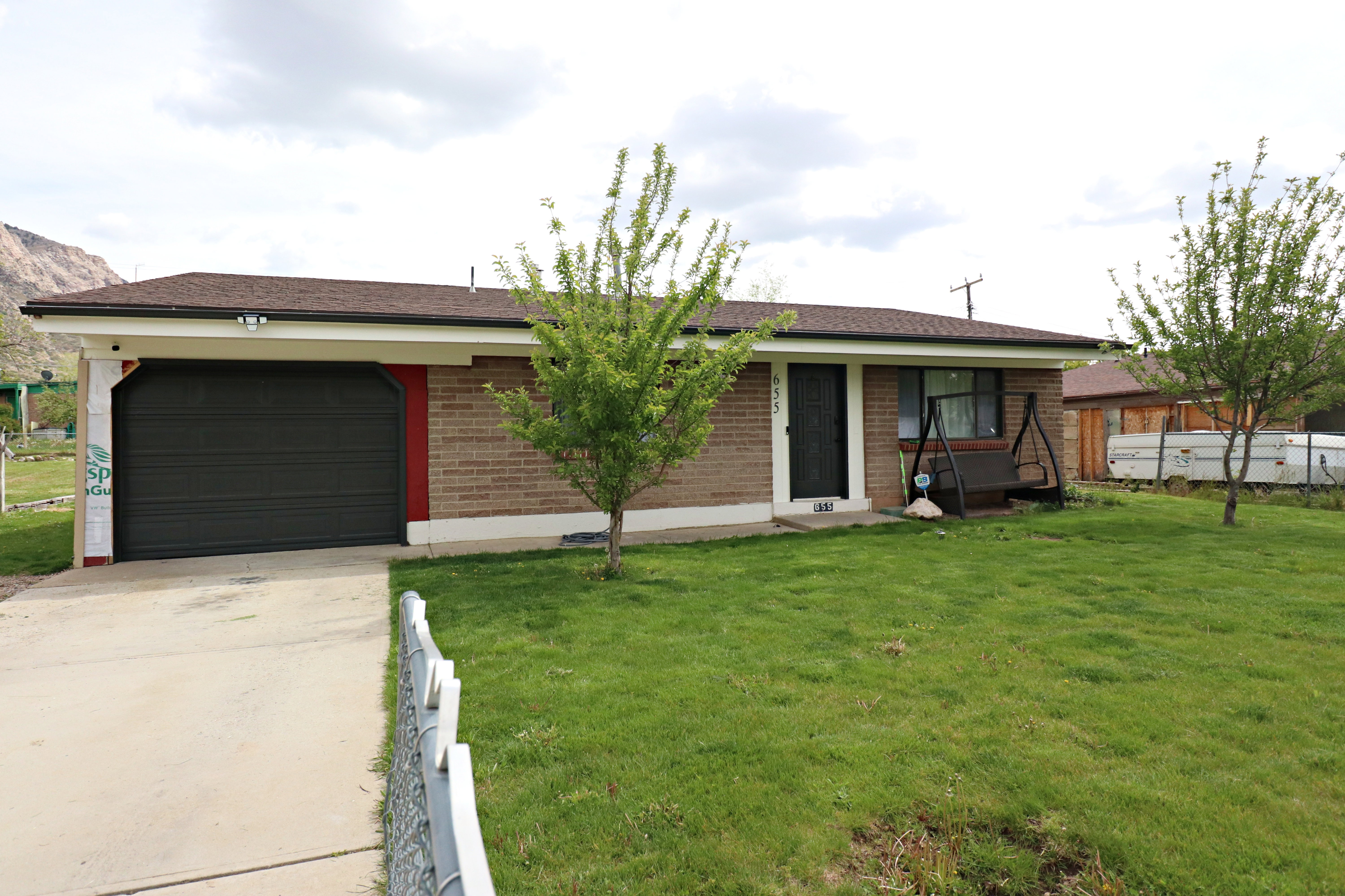 Ranch-style home with brick siding, concrete driveway, a front lawn, and a garage