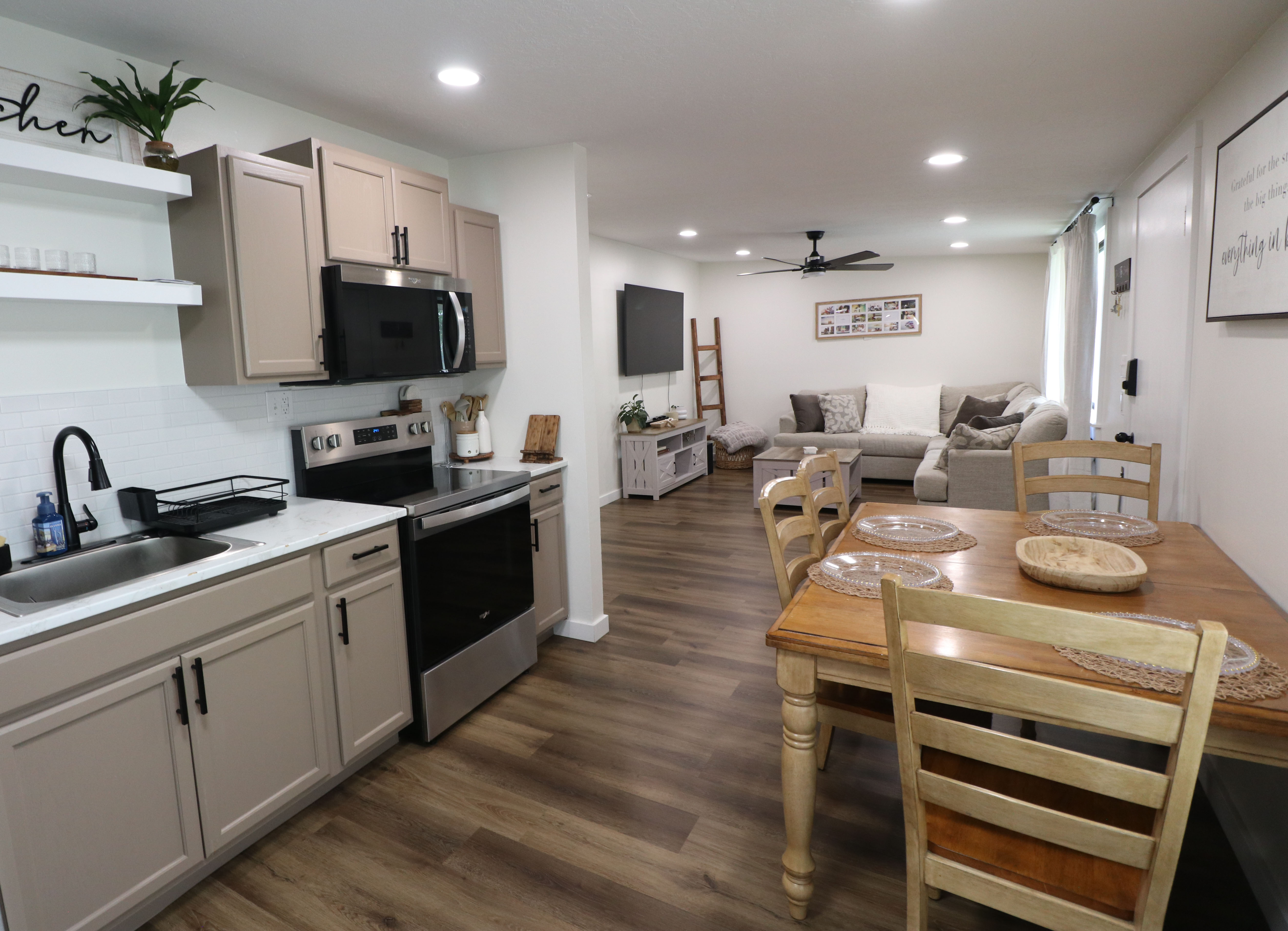 Kitchen with stainless steel appliances, open floor plan, open shelves, dark wood-style flooring, and ceiling fan