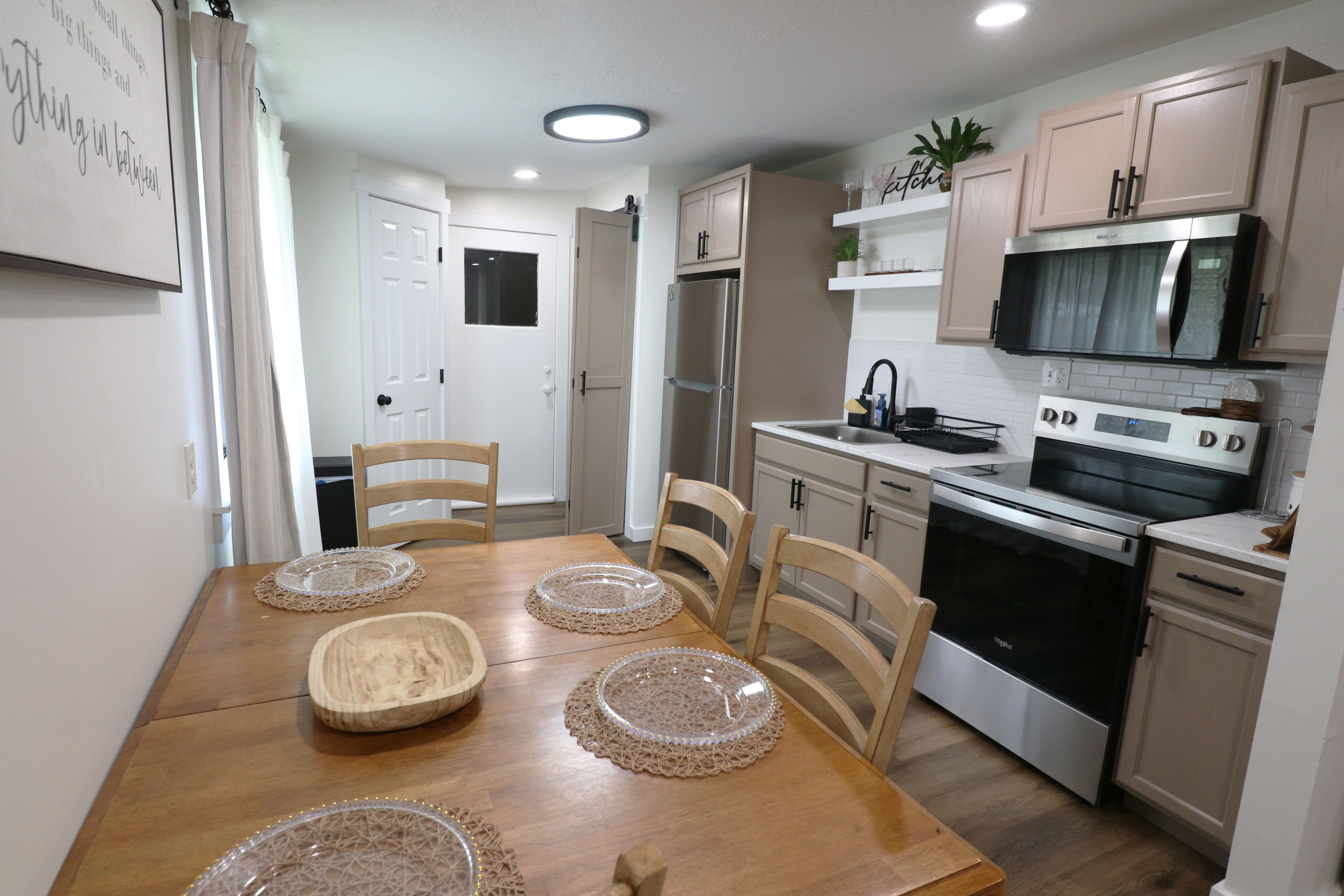 Kitchen with stainless steel appliances, light countertops, open shelves, backsplash, and recessed lighting