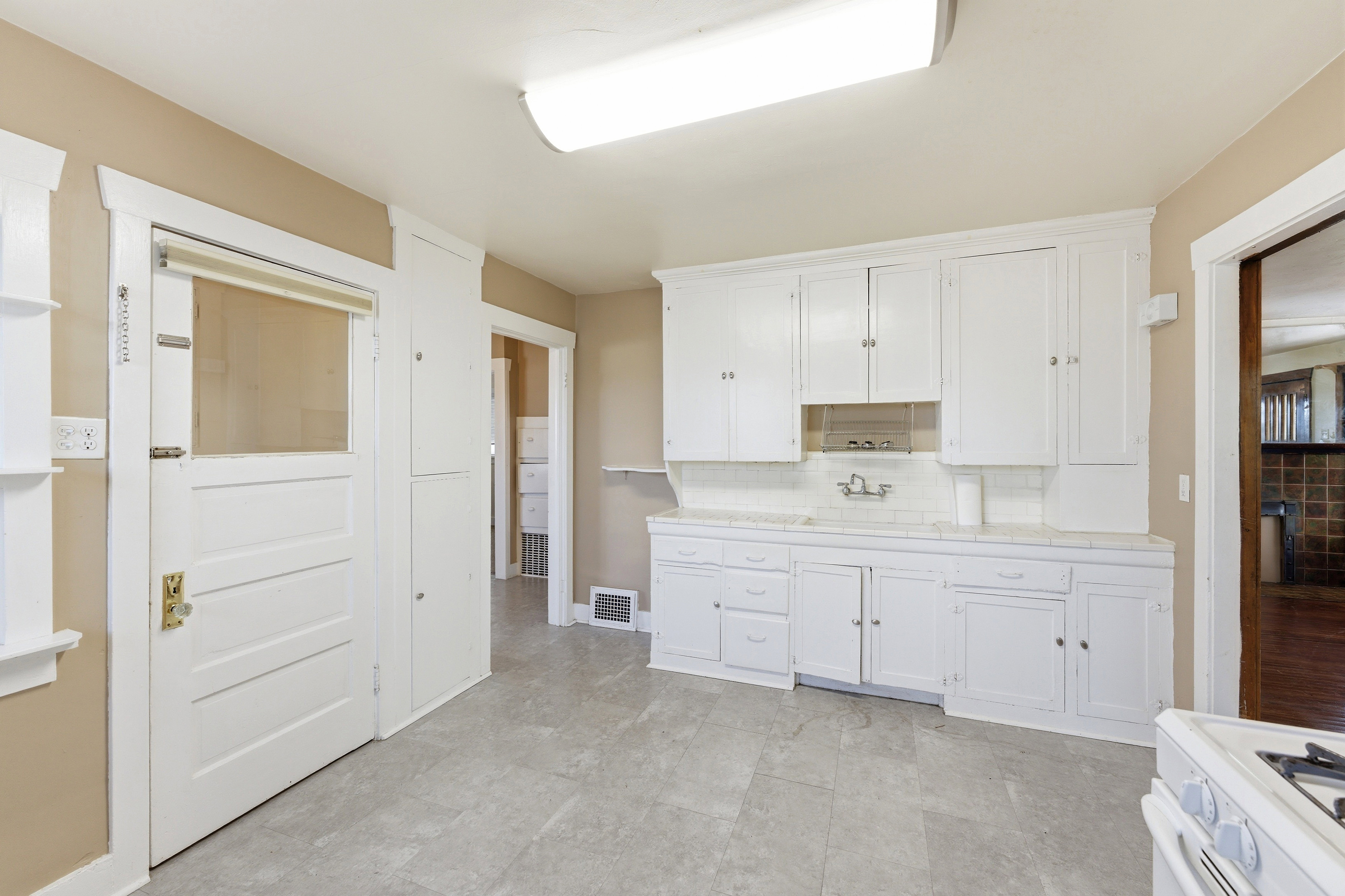 Kitchen featuring white cabinets, white range with gas cooktop, light countertops, and backsplash