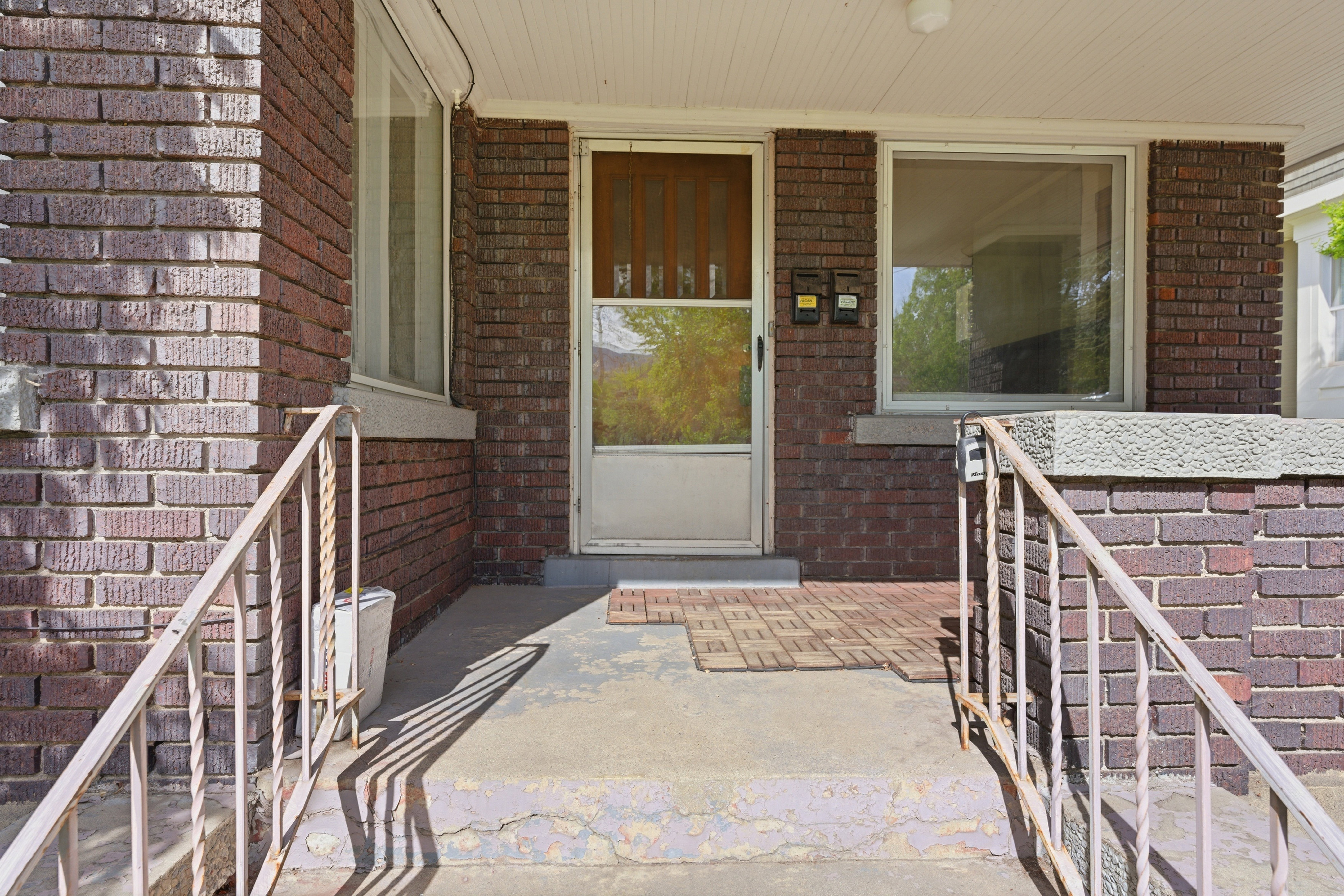 View of exterior entry with brick siding and a porch