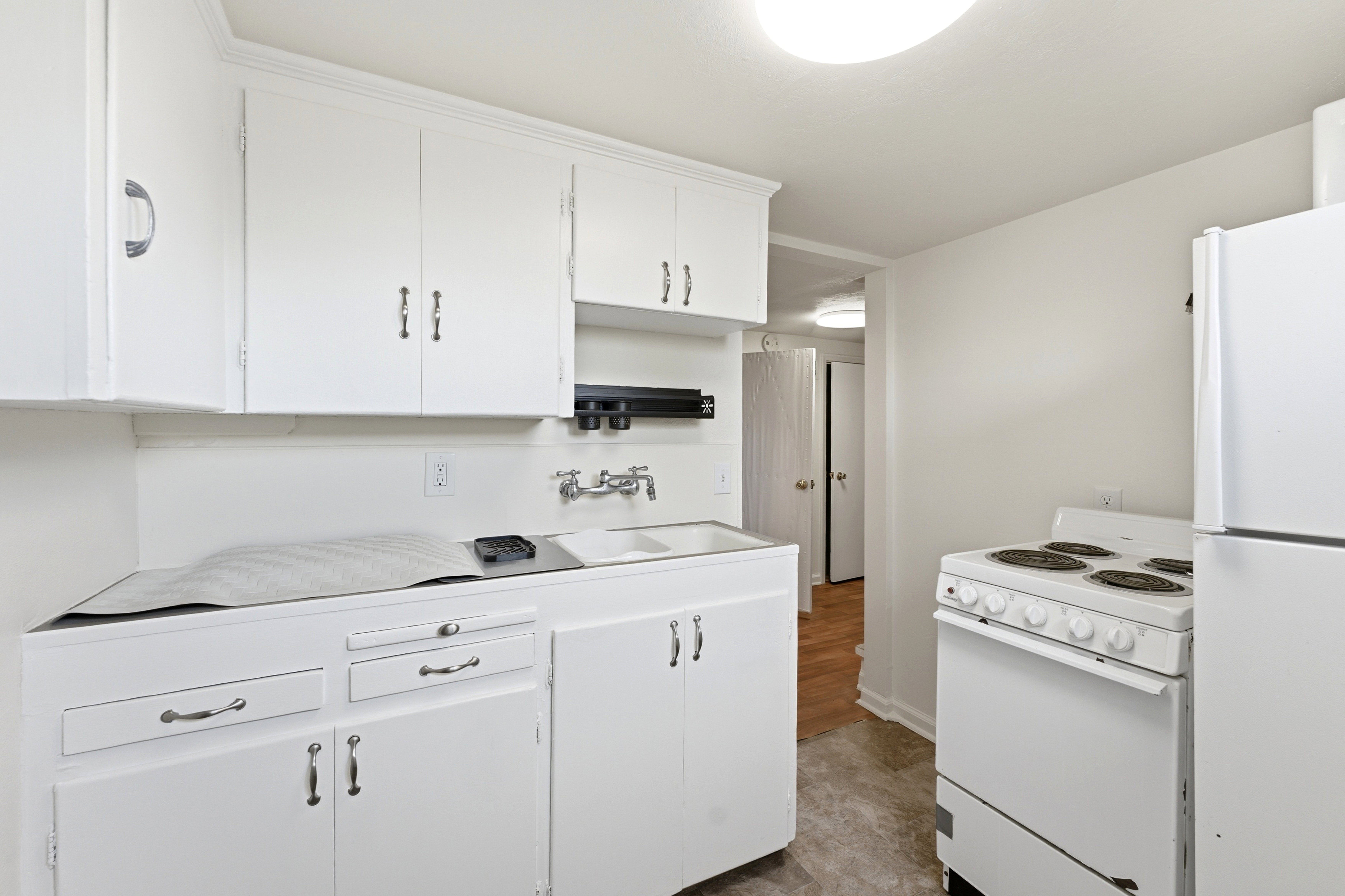 Kitchen with white appliances, white cabinetry, and light countertops