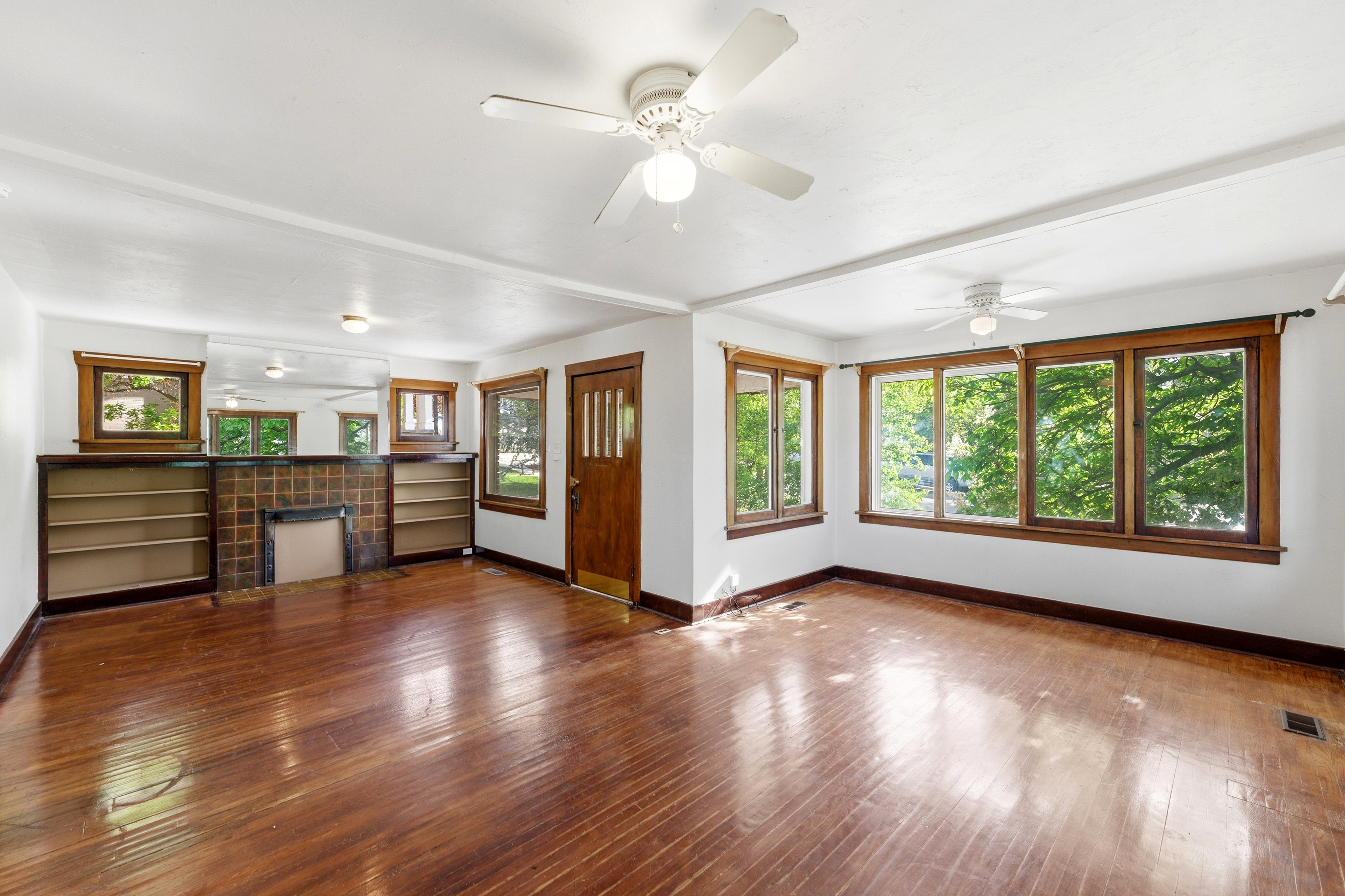 Unfurnished living room featuring dark wood finished floors, a ceiling fan, and a tiled fireplace