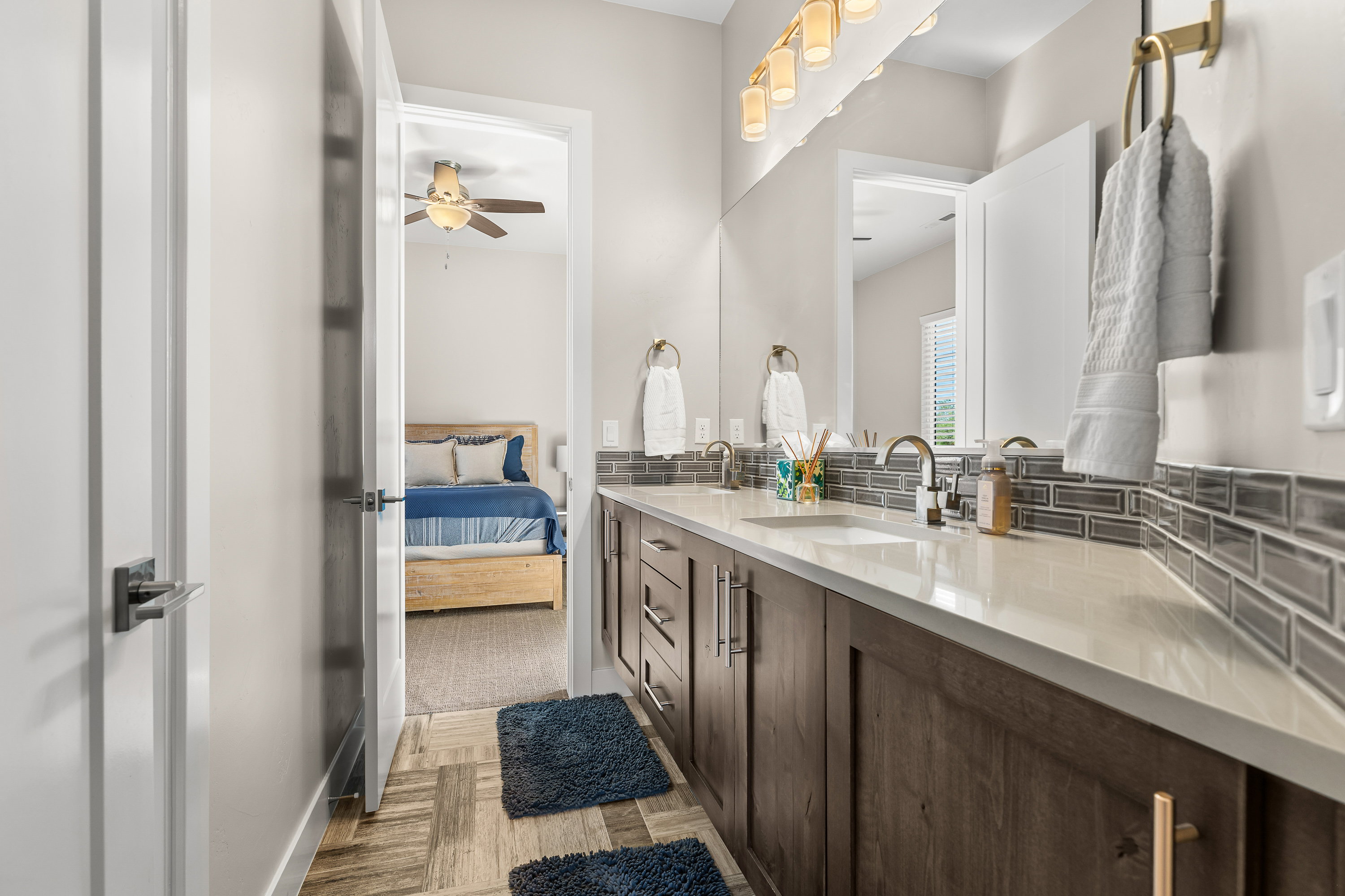 Ensuite bathroom featuring double vanity, light wood finished floors, and a ceiling fan