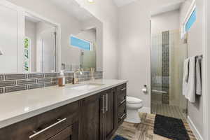 Bathroom with a stall shower, vanity, and decorative backsplash
