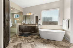 Bathroom with vanity, a freestanding bath, a stall shower, and recessed lighting