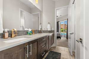 Full bathroom with double vanity, ensuite bath, and decorative backsplash