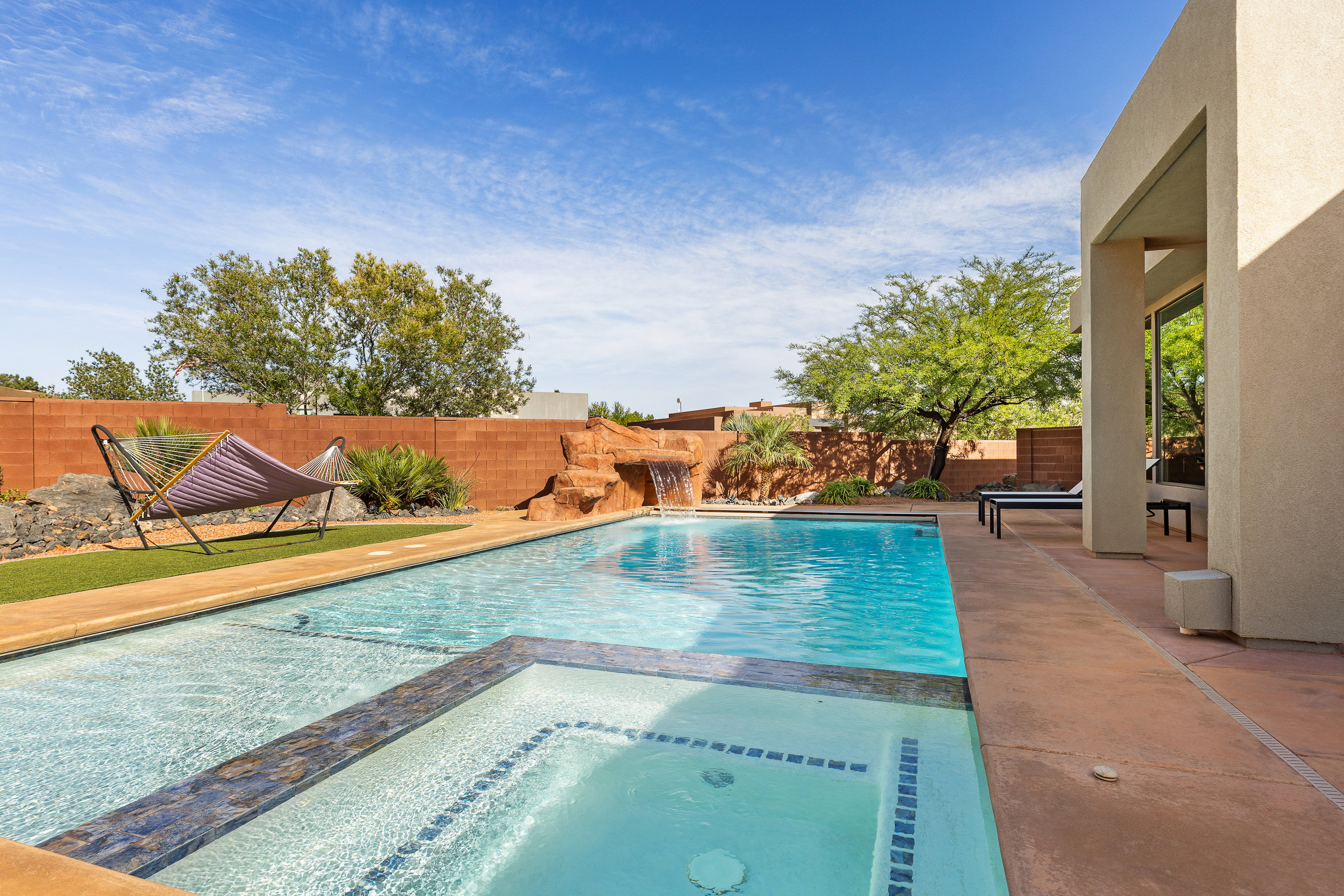 Combined pool / hot tub with a patio area and a fenced backyard
