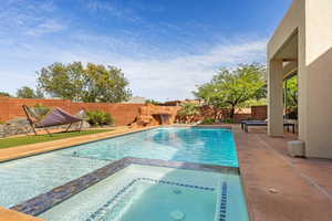 Combined pool / hot tub with a patio area and a fenced backyard
