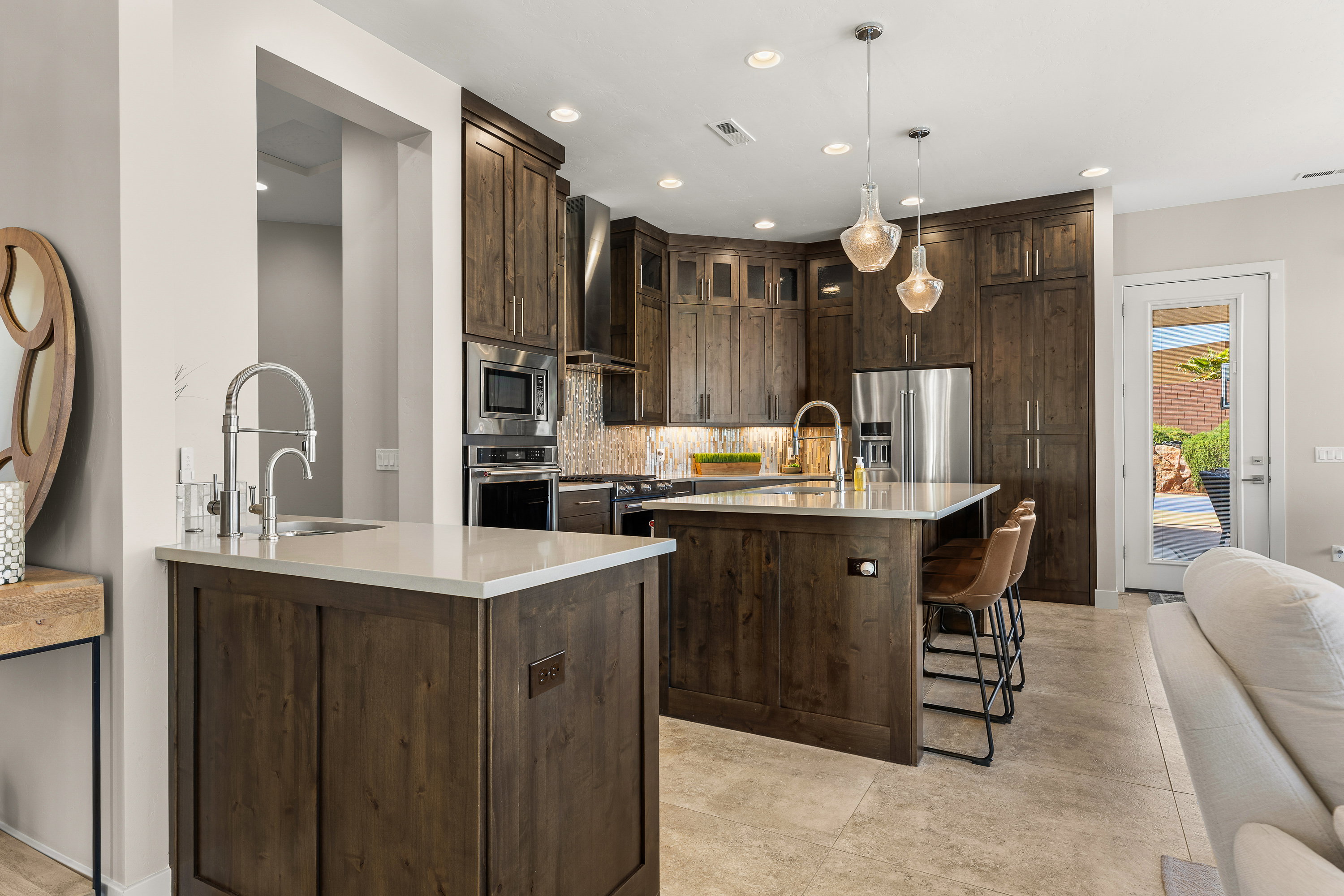 Kitchen featuring dark wood finish cabinetry, a kitchen bar, light stone counters, premium appliances, and decorative backsplash