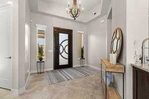 Entrance foyer featuring a tray ceiling and a chandelier