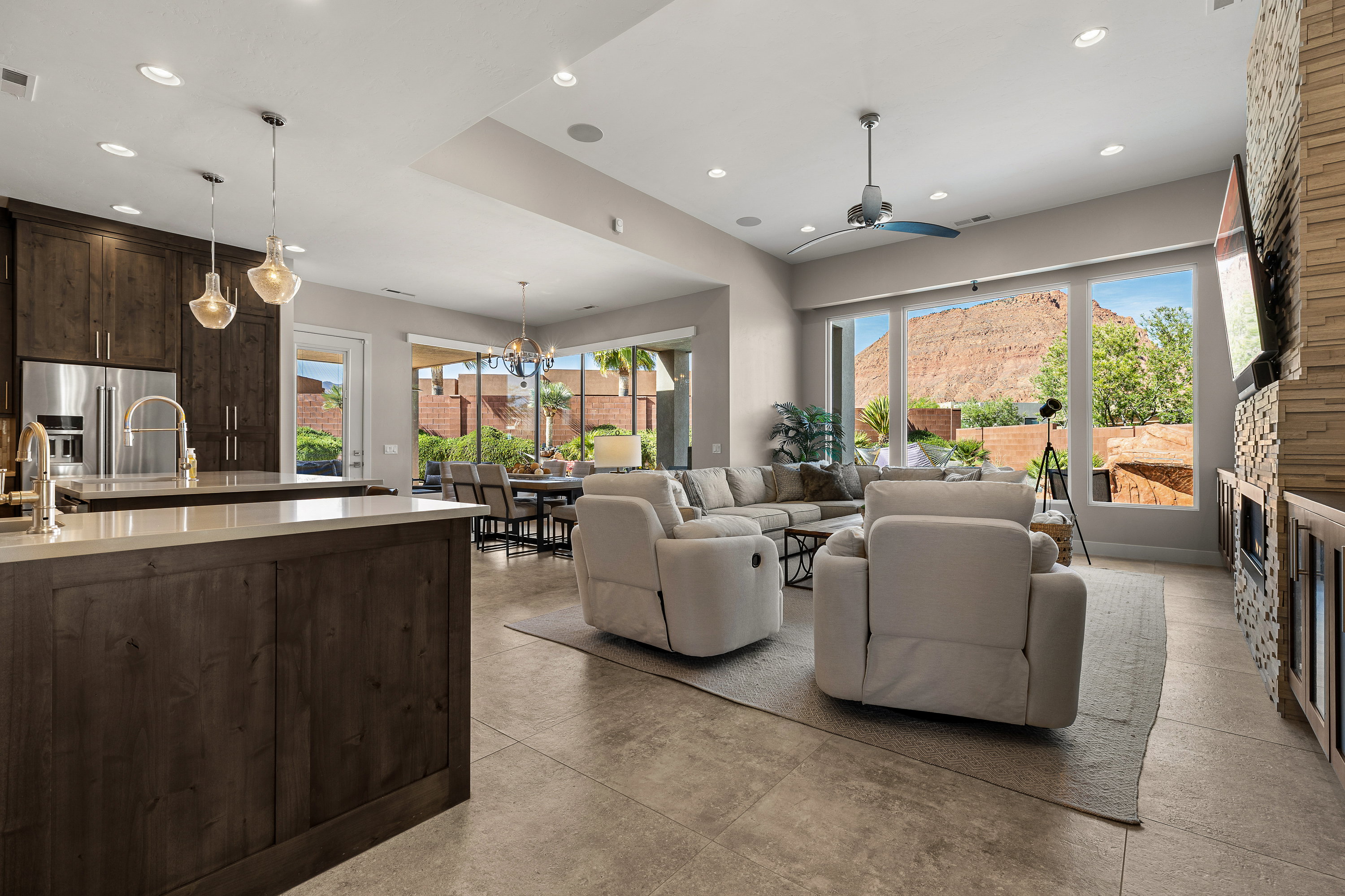 Living room with a stone fireplace, ceiling fan, and a chandelier