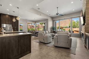 Living room with a stone fireplace, ceiling fan, and a chandelier