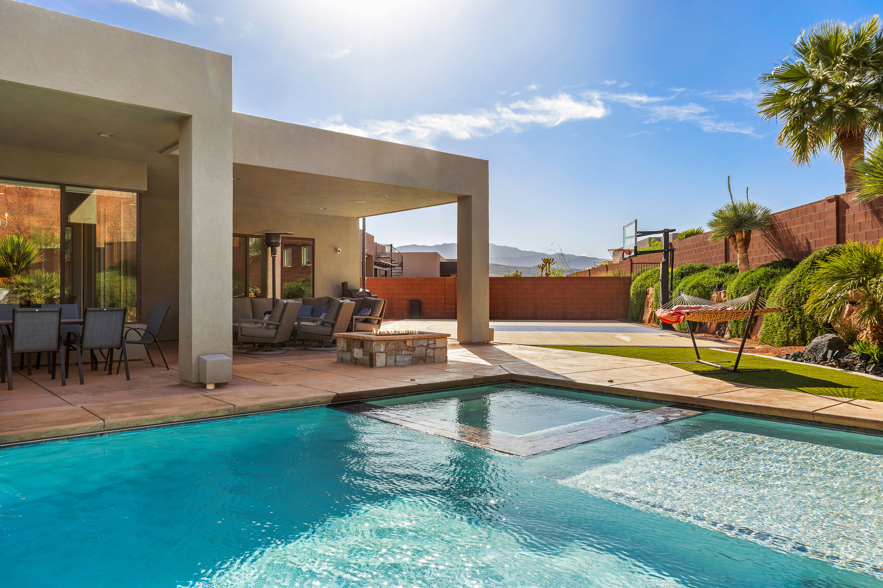 Integrated pool / spa with a patio, a mountain view, a fenced backyard, and an outdoor living space with a fire pit