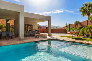 Integrated pool / spa with a patio, a mountain view, a fenced backyard, and an outdoor living space with a fire pit