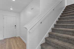 Staircase featuring wood finished floors and recessed lighting
